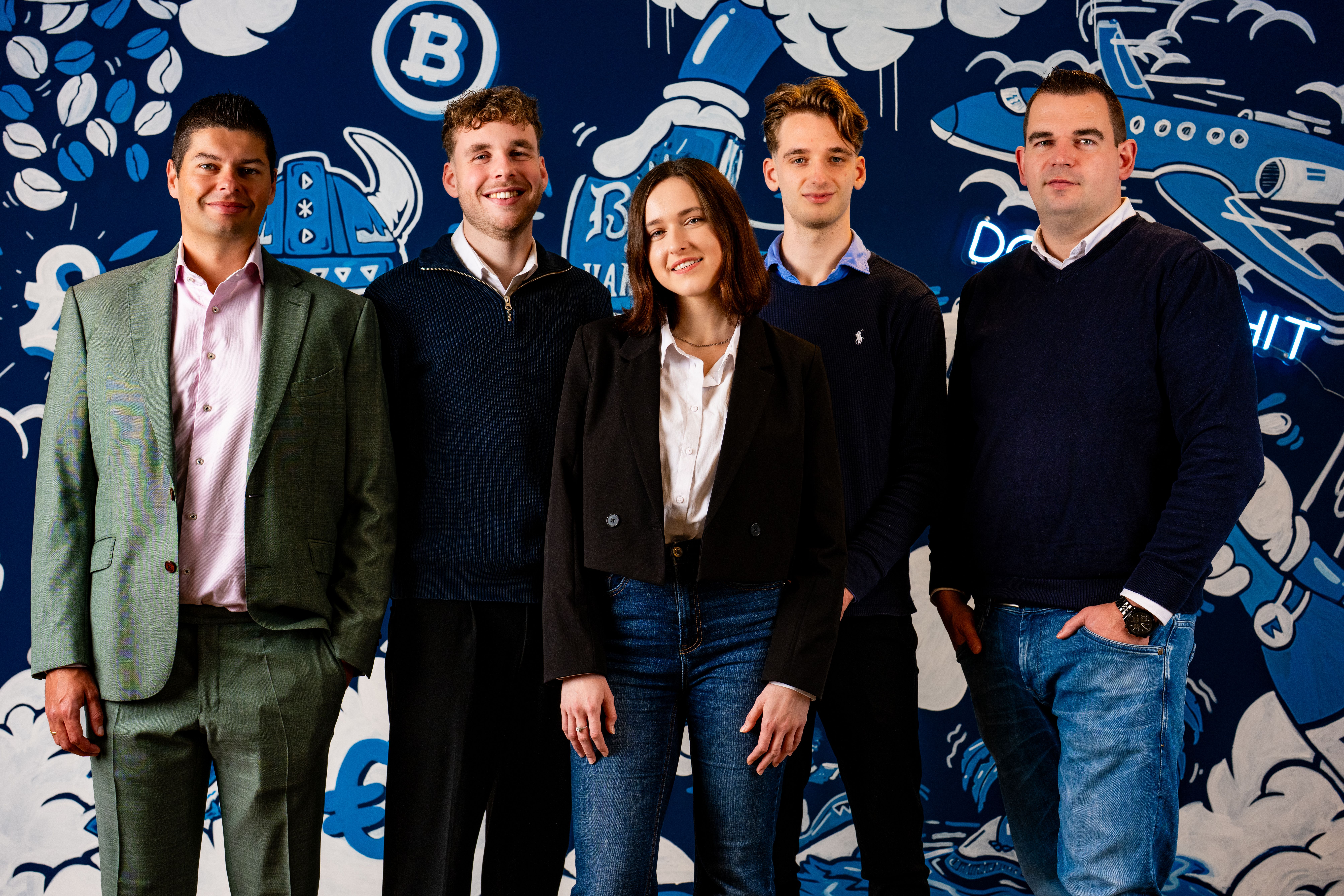 Het team van Blauwtand voor de blauwe muur op hun kantoor.