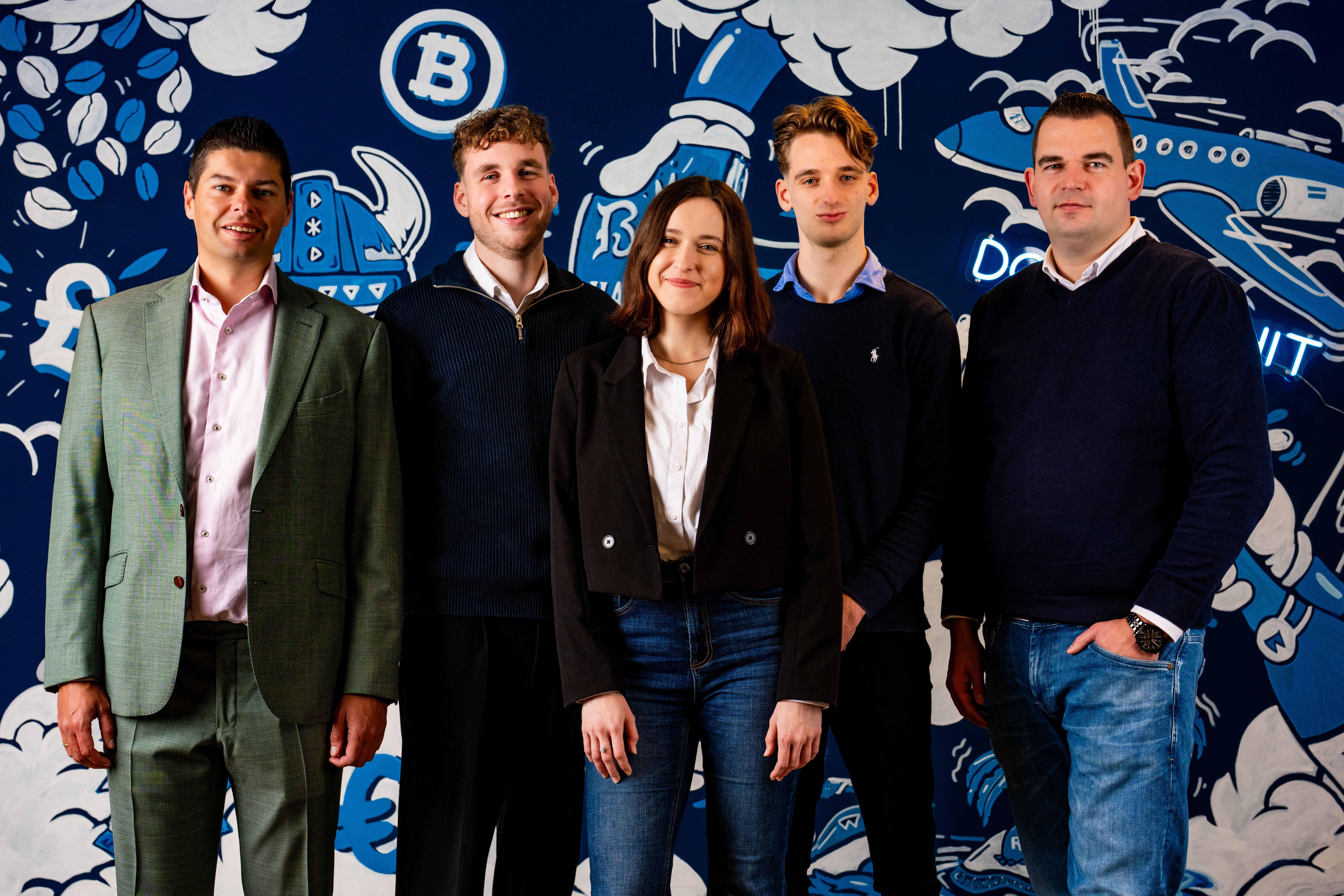 Team van Blauwtand IT voor hun blauwe muur op kantoor